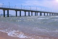 View on sea sand beach with waves pier coastal city and mountains at sunny day. Royalty Free Stock Photo