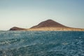 Beautiful coastal view of Montana Roja - Red Mountain. Shining clear blue sky over Horizon line, wave ripples on the turquoise