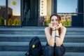 Beautiful College student girl sitting on the steps and laughing looking at camera. Portrait of a cheerful high school girl Royalty Free Stock Photo