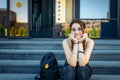 Beautiful College student girl sitting on the steps and laughing looking at camera. Portrait of a cheerful high school girl Royalty Free Stock Photo