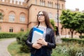 Ready for new knowledge. Beautiful college student holding notebooks and smiling outdoors on Uni background Royalty Free Stock Photo