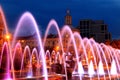 Beautiful colored dancing fountain in evening, show fountains at night against background of buildings, towers, skyscrapers, Royalty Free Stock Photo