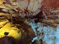 Beautiful colorful cave interior with ancient stalactites and stalagmites. Vertical image Royalty Free Stock Photo