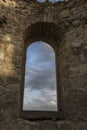 Beautiful colorful clouds on blue sky on sunset. View through arched window in old stone abandoned church. ÃÂrchitecture