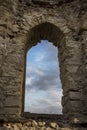 Beautiful colorful clouds on blue sky on sunset. View through arched window in old stone abandoned church. ÃÂrchitecture