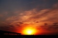 Beautiful colorful dramatic sky with clouds at sunset. Bright orange setting sun low on the horizon. Cirrus clouds Royalty Free Stock Photo