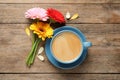 Beautiful colorful gerbera flowers, petals and cup of coffee on wooden table, flat lay Royalty Free Stock Photo