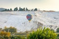 Beautiful colorful hot air balloon on background of white mountains of Pamukkale in Turkey. Cascade of terraced baths