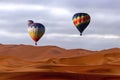 Beautiful Colorful Hot Air Baloons and dramatic clouds over the sand dunes in the desert Royalty Free Stock Photo