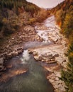 Beautiful colorful landscape with a stream and forest in autumn colors, mountains in the background. Royalty Free Stock Photo