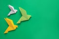 Beautiful colorful origami birds on green background, flat lay. Space for text Royalty Free Stock Photo