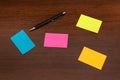 Beautiful colorful sticky notes and pen on brown wooden desk Royalty Free Stock Photo