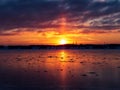 Beautiful colorful sunrise on the freezing weather forming light pillar above sun over the frozen river with beautiful reflection Royalty Free Stock Photo