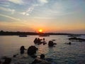 Beautiful colorful sunset on a choppy sea, silhouette of rock and fishing boats set out to catch fish.