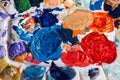 Beautiful colorful textured paints background. Paint strokes and left overs residues of paints in palette colour array on a table