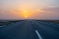 Beautiful colourful sunset over endless empty road in middle of desert. Asphalt highway in Tunisia, North Africa. Royalty Free Stock Photo