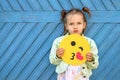 Beautiful comical girl sends an air kiss holding yellow funny emoticon in hand