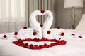 Beautiful composition on bed. Swans made of towels and rose arranged in heart shape Royalty Free Stock Photo