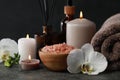 Beautiful composition with burning candles and different spa products on dark grey table Royalty Free Stock Photo