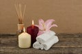 Beautiful composition with burning candles, pink lily and spa towels on wooden background