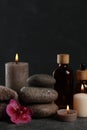 Beautiful composition with burning candles, spa stones and different care products on dark grey table Royalty Free Stock Photo