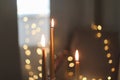 Beautiful composition with burning wax candles on table. Elegant golden candlesticks with burning candles in a cozy room