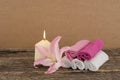 Beautiful composition with candle, pink lily flower and spa towels on wooden background