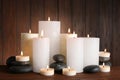 Beautiful composition with candles and stones against wooden background Royalty Free Stock Photo