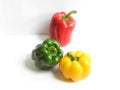 Beautiful composition of fresh bell peppers in glossy green, red and yellow colors on a white background with their lighting and s