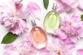 Beautiful composition with perfume and flowers. Perfume bottle, pink flowers peonies green leaves on light background top view Royalty Free Stock Photo