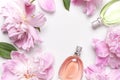 Beautiful composition with perfume and flowers. Perfume bottle, pink flowers peonies green leaves on light background top view Royalty Free Stock Photo