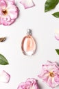 Beautiful composition with perfume and flowers. Perfume bottle, rose flowers petals green leaves on light background top view Flat Royalty Free Stock Photo