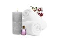 Beautiful composition with rolled towels, orchid flowers and burning candle on white background. Spa therapy Royalty Free Stock Photo