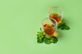 Beautiful composition with two double wall glasses of tea and mint leaves on a green backdrop Royalty Free Stock Photo