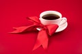Beautiful composition with a white Cup and a red satin bow on a red background. Romantic background. Royalty Free Stock Photo