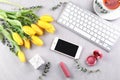 Beautiful composition with yellow tulips, gift, keyboard and mobile phone on grey background