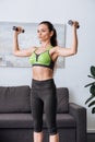 Beautiful concentrated sportswoman training with dumbbells