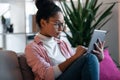 Beautiful concentrated young entrepreneur woman using her digital tablet while sitting on couch in the office Royalty Free Stock Photo