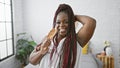 Beautiful and confident african american woman enjoying her morning, singing her favorite song using a brush as a microphone in