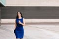 Beautiful confident Hispanic businesswoman with smile walking outdoors near office building with coffee in hand