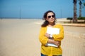 Beautiful confident Hispanic freelancer wearing sunglasses, holding laptop and smiling cutely looking at the camera Royalty Free Stock Photo