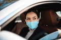 Beautiful confident pleased businesswoman in face mask driving car