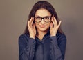 Beautiful confident thinking smiling business brunette woman holding two hands the glasses on the face in blue shirt on grey Royalty Free Stock Photo