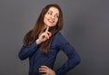 Beautiful confident thinking toothy smiling business woman with finger under the face in blue shirt on grey background with empty Royalty Free Stock Photo