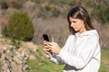 Beautiful confused brunette woman reads news on the smartphone in a park on a sunny day.