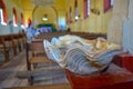 Huge seashell as a bowl for sacred water in Catholic church. Empty seats in the holy mass hall