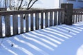Beautiful contrasting blue shadow of a wooden rustic fence on the white snow on a sunny winter day. Background. Abstract Royalty Free Stock Photo