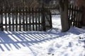 Beautiful contrasting blue shadow of a wooden rustic fence on the white snow on a sunny winter day. Background. Abstract Royalty Free Stock Photo