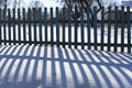 Beautiful contrasting blue shadow of a wooden rustic fence on the white snow on a sunny winter day. Background. Abstract Royalty Free Stock Photo