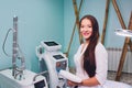 Beautiful cosmetician in medical gloves is showing her workplace, looking at camera and smiling.